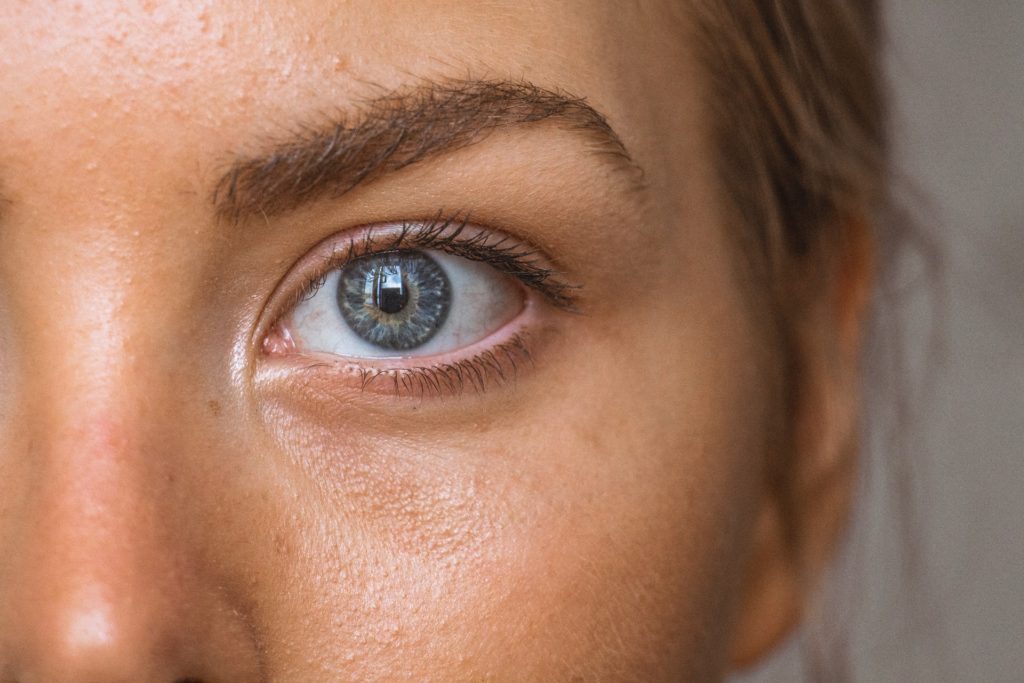 Close up of a woman's eye, cheek and eyebrow shows clean skin makes skin glow without makeup