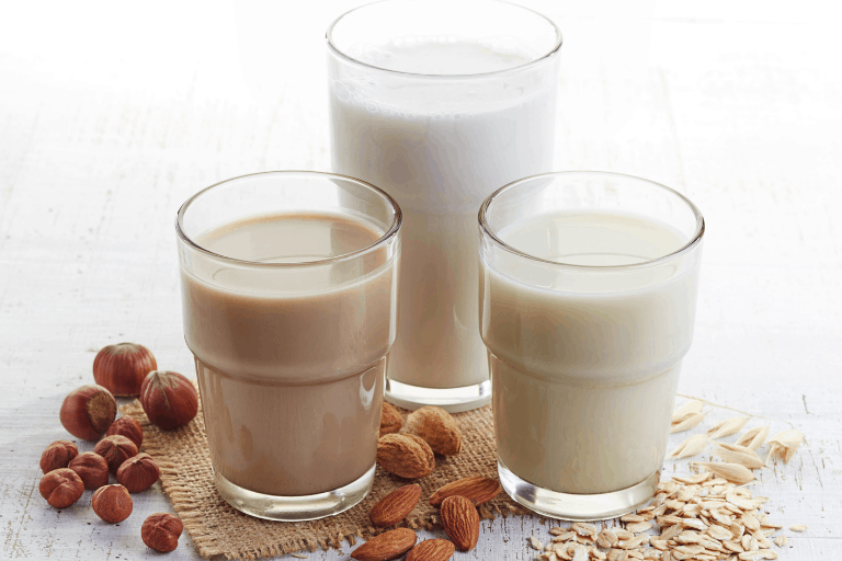Three glasses of oat milk, almond milk, and macadamia milk
