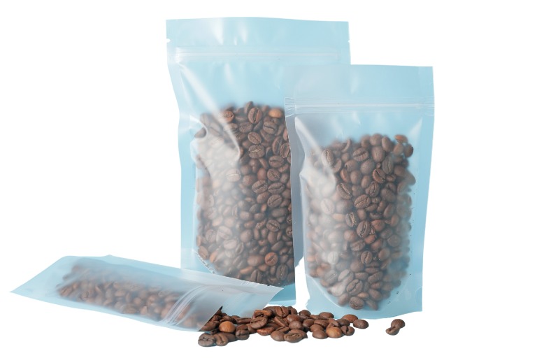 Clear bags of coffee beans, with one knocked over and coffee spilling out