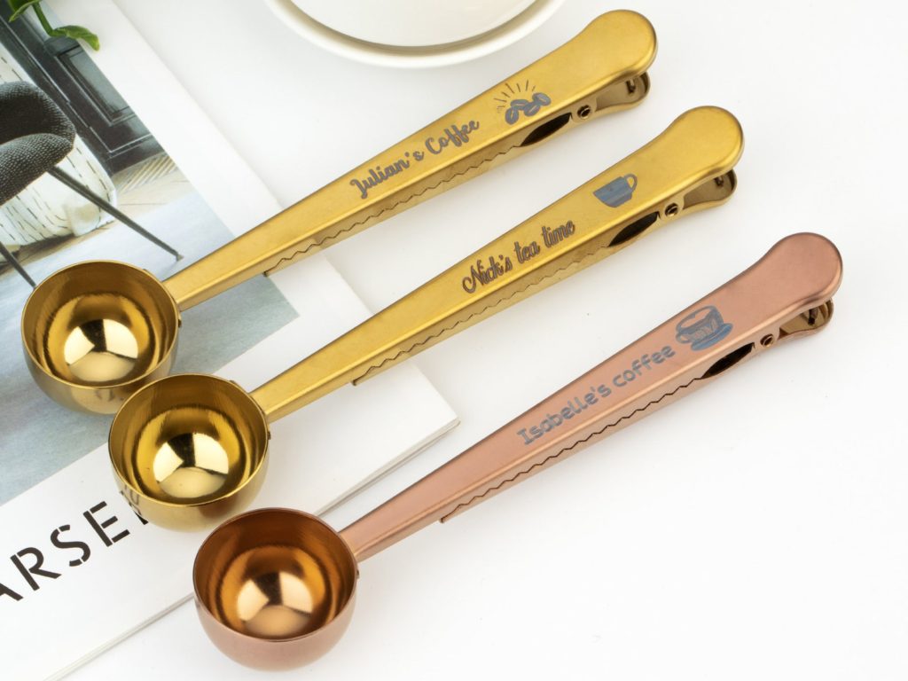 Gold, bronze, and rose gold coffee scoops that double as a coffee bag clip