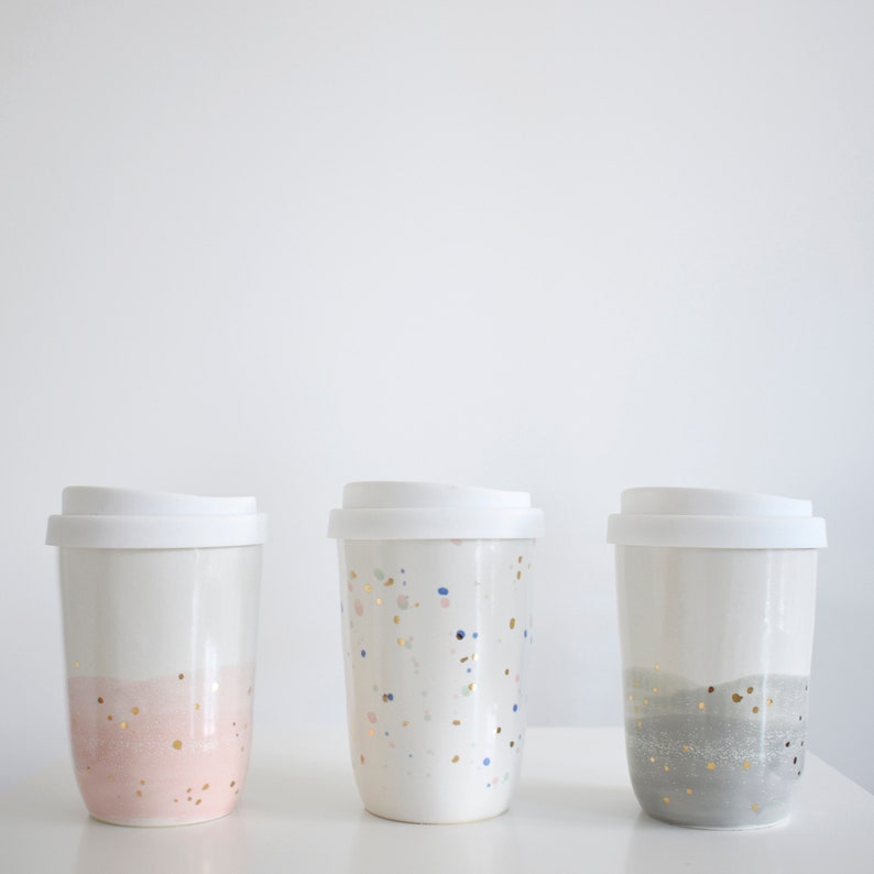 Three ceramic coffee cups with silicone lids, with speckled designs in plain, pink or gray