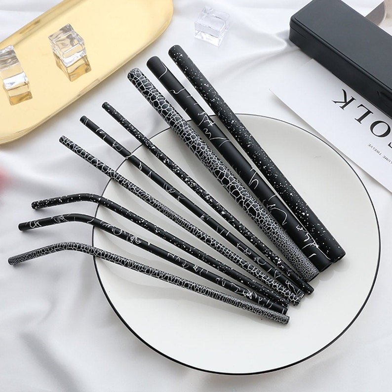 Black metal straw set with different patterns, some bent and some straight