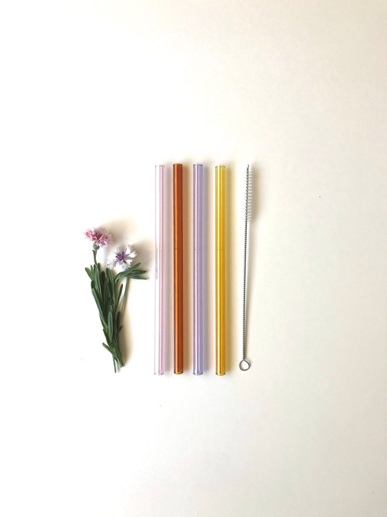 Four glass straws in amber, yellow, lavender and pink, with a straw cleaner brush