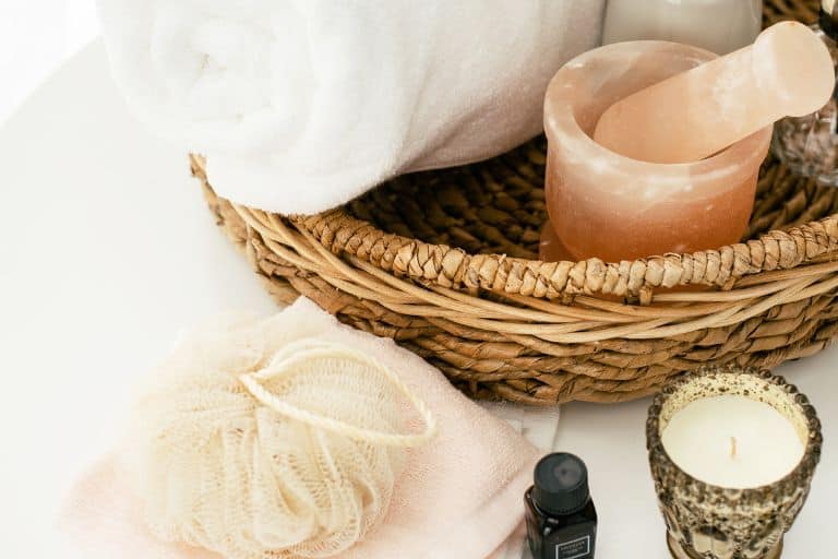 Whicker basket with self care items such as a towel, loufa, essential oils and candle